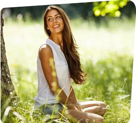 Foto einer jungen Frau, sie sitzt lächelnd auf
dem Rasen